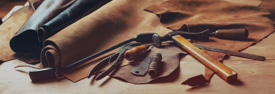 Various leather craft tools laid on the table with several leather fabrics.