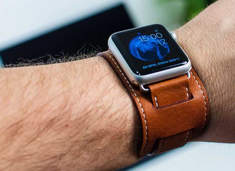 Smartwatch with leather armbindel wrapped around a mans hand.