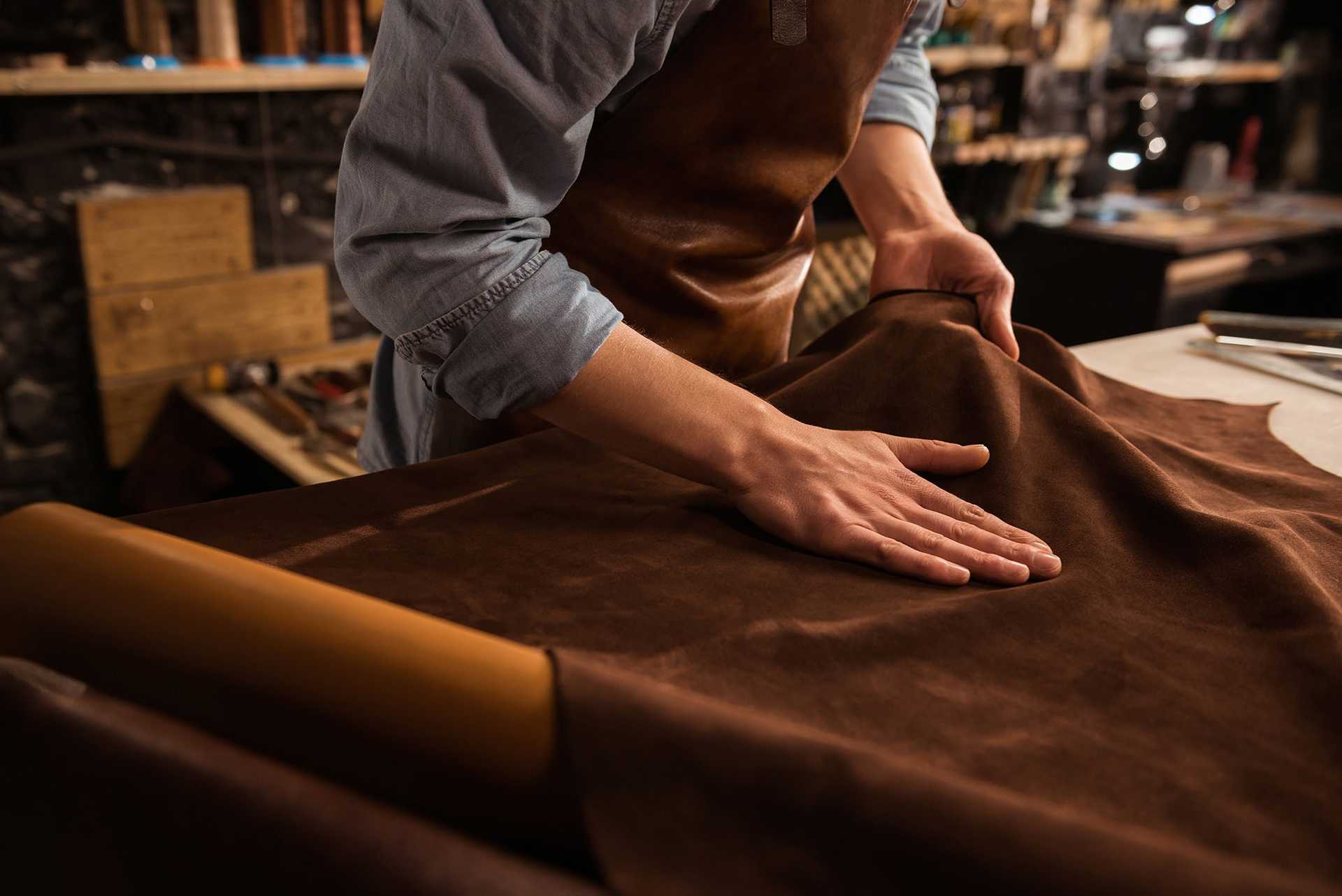 Leather worker stroking his hand over leather garment.